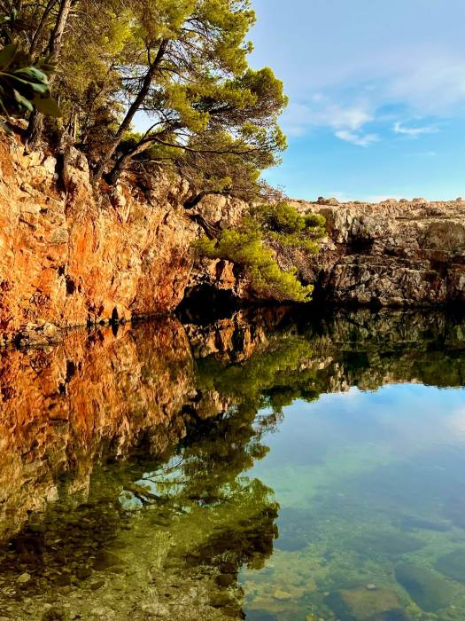 A clear, tranquil salty water pool under a bright blue sky on Lokrum Island.