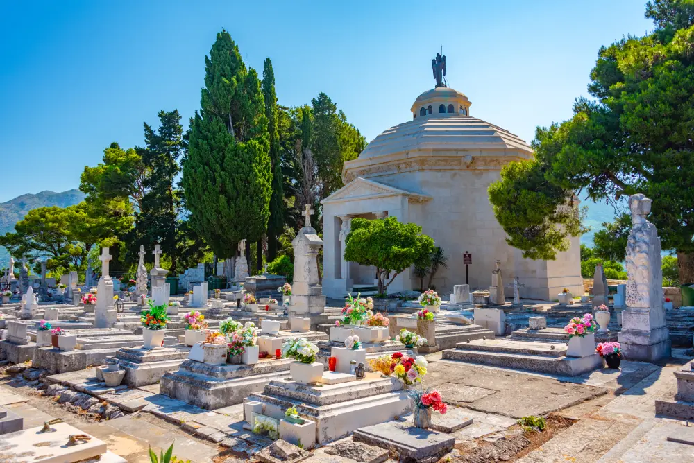 Cemetery in Cavtat with white stone graves adorned with colourful flowers.