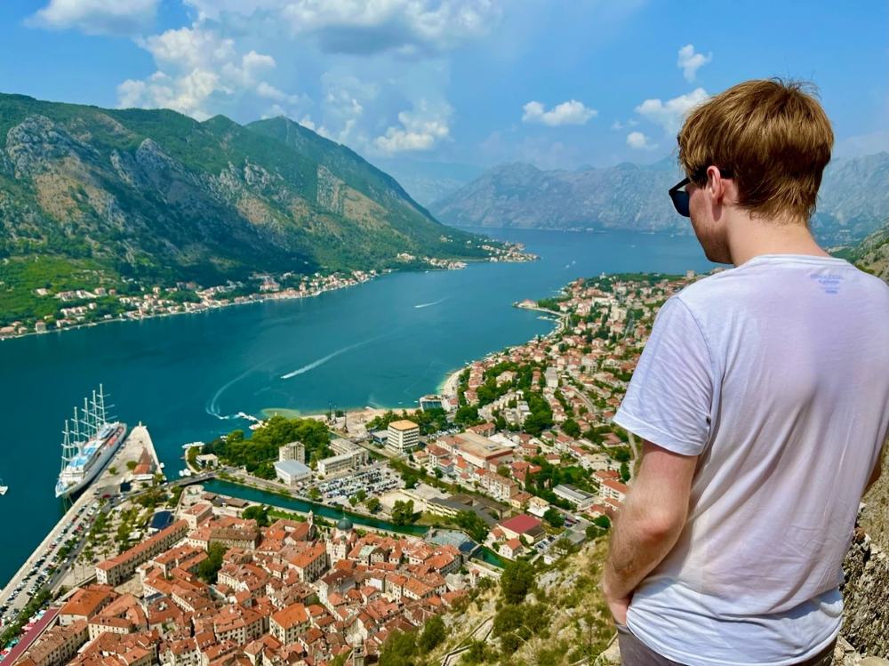 Person standing overlooking a panorama of The Bay of Kotor Old Town