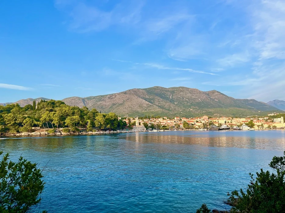 A panoramic view of Cavtat Old Town, showcasing its historic architecture with a backdrop of lush hills fronted by the serene blue waters of the Adriatic Sea.