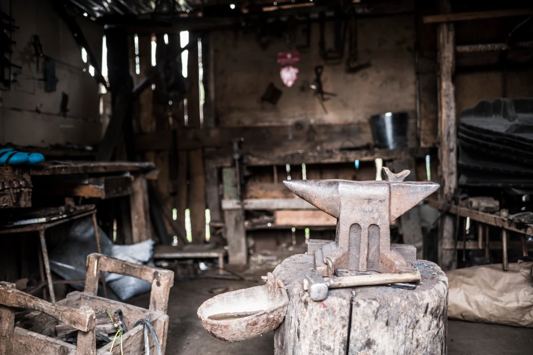 An anvil and hammer resting on a wooden stump in a rustic blacksmith workshop in Viscri Village, Romania