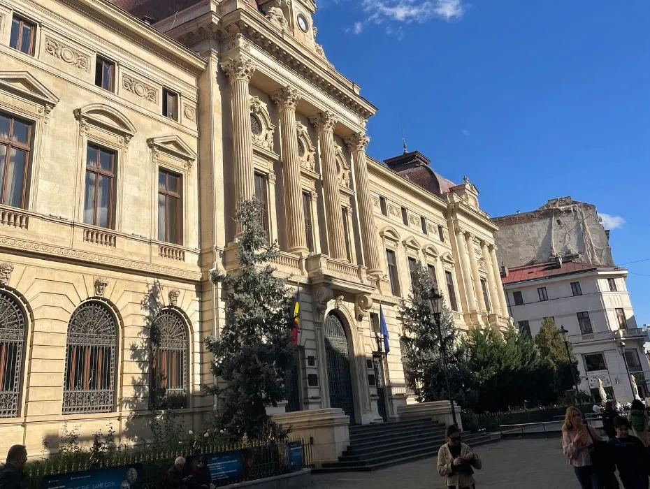Classic European architecture on display at the Bucharest Old Town, with pedestrians strolling by on a sunny day, highlighting the city's historical charm and vibrant urban life